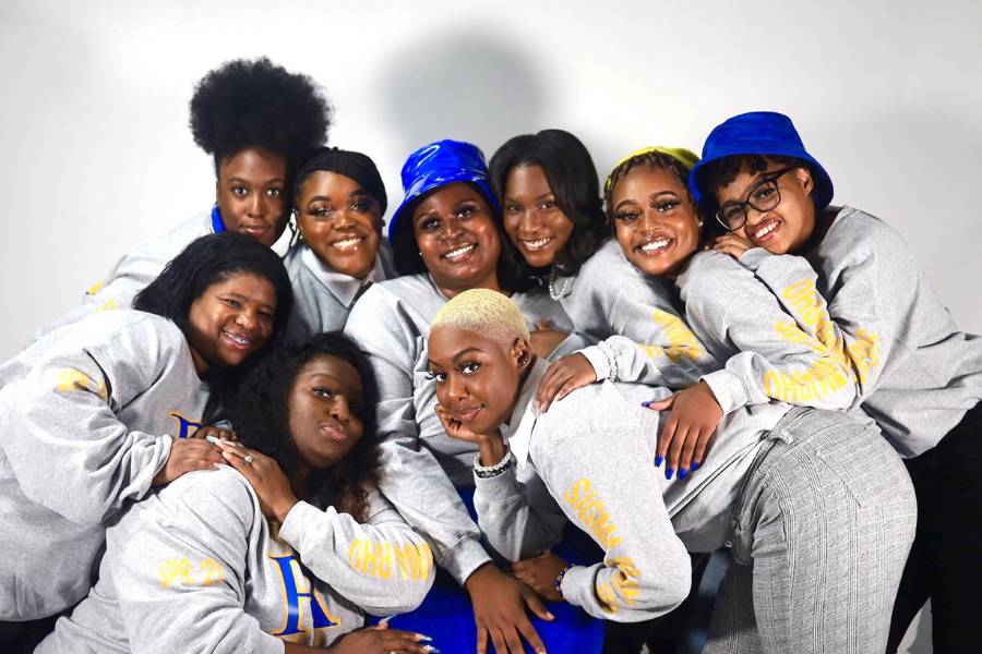Image of the Rho Lambda Chapter of Sigma Gamma Rho in gray sweatershirts with their greek letters; several are wearing blue bucket hats