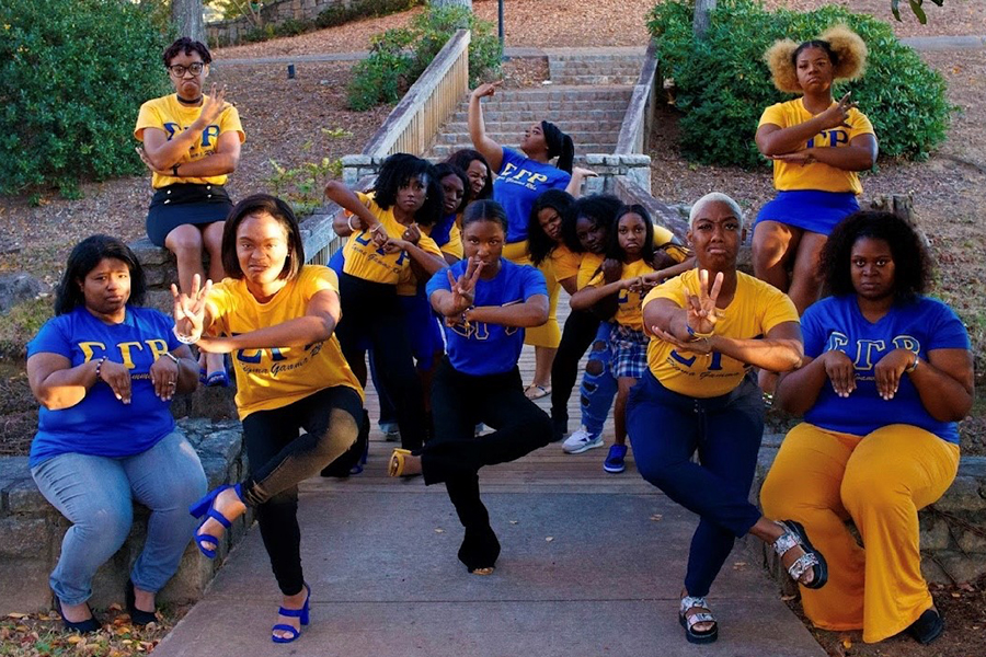 Image of members of the Rho Lambda Chapter of Sigma Gamma Rho showing hand signs for the organization at a bridge.