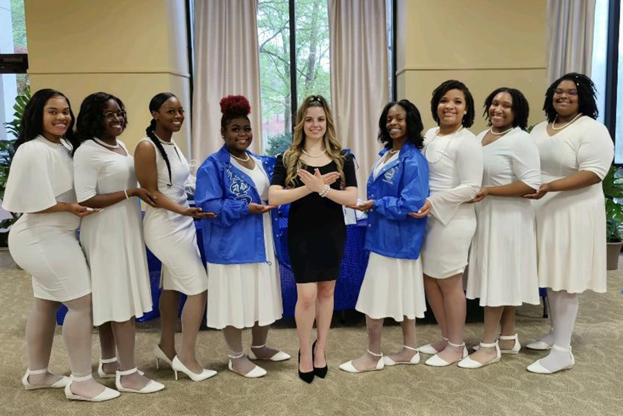 Image of teh Iota Sigma Chapter of Zeta Phi Beta Sorority, Inc. dressed in all white, except the president who is in blue