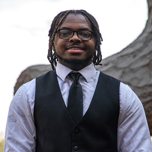 Image of D'Montrail McGill wearing a white dress shirt under a black vest and tie