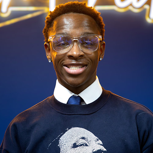 Image of Johnny Daniel, Jr. wearing a Martin Luther King, Jr shirt over a white dress shirt and navy tie