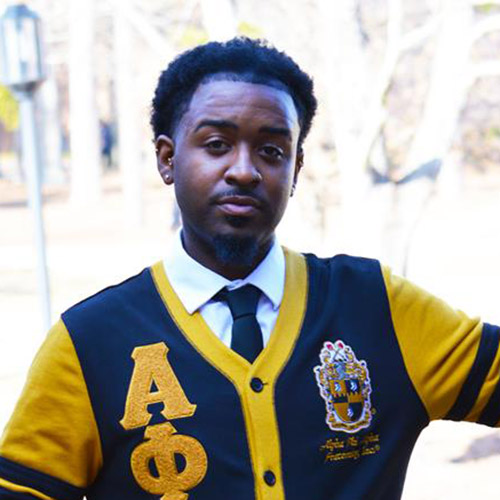 Image of Kymani Goddard, wearing an Alpha Phi Alpha cardigan